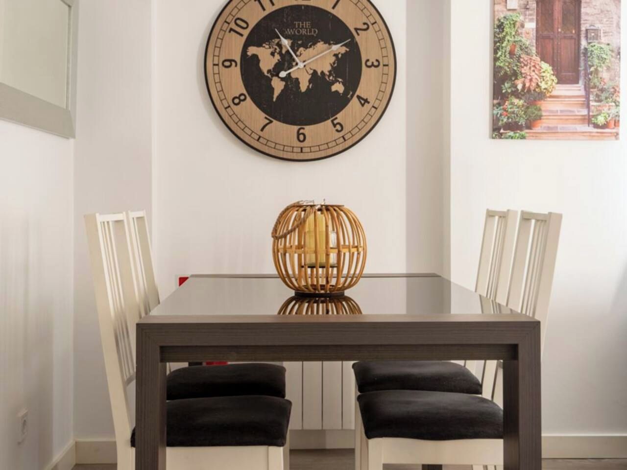 Un coin repas avec une horloge murale ronde, un globe terrestre et une table entourée de chaises.