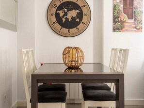 A dining area with a round wall clock, a globe, and a table with chairs. - Apartamento Atalaya en el centro (Santander)