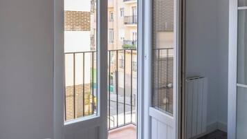 A room with a large window, a radiator, and a door leading to a balcony.