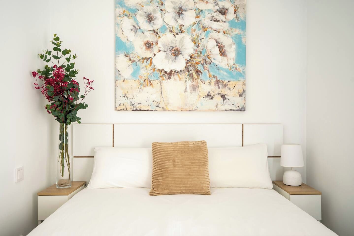 Een hotelkamer met een bed, een nachtkastje, een lamp en een aan de muur hangend schilderij.