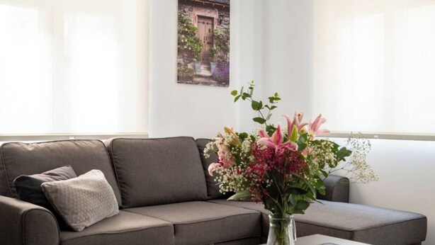 A modern living room with a grey sofa, a glass coffee table, and a vase of flowers. - Apartamento Atalaya en el centro (Santander)