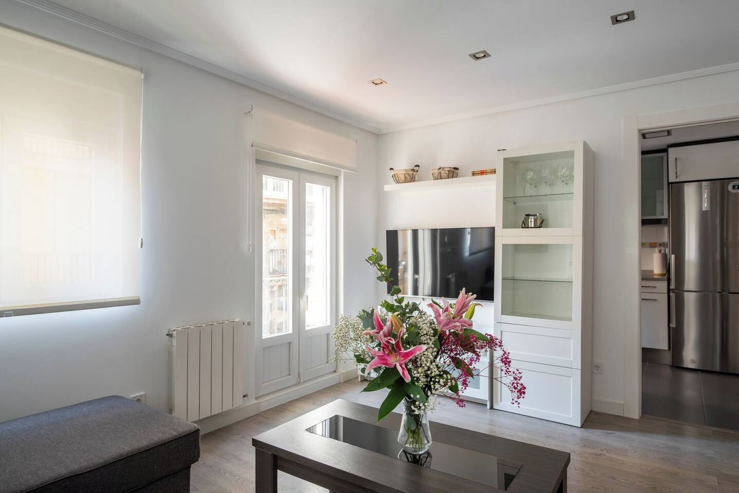 A modern kitchen with a built-in oven, a refrigerator, and a dining area with a table and bench.