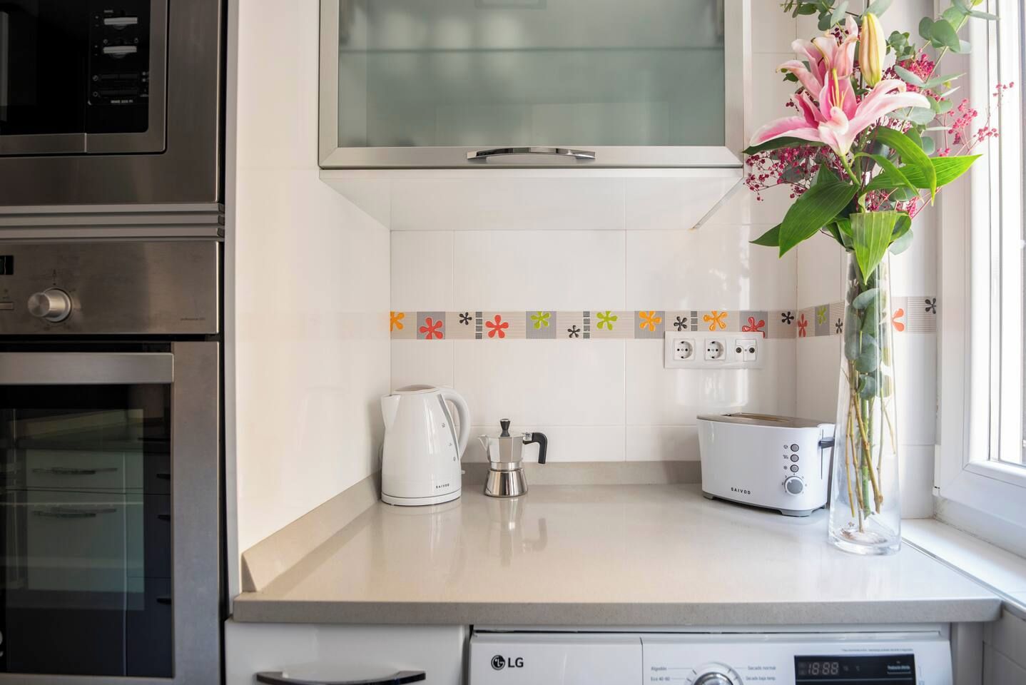 Una cocina equipada con microondas, tetera, tostadora y lavavajillas.