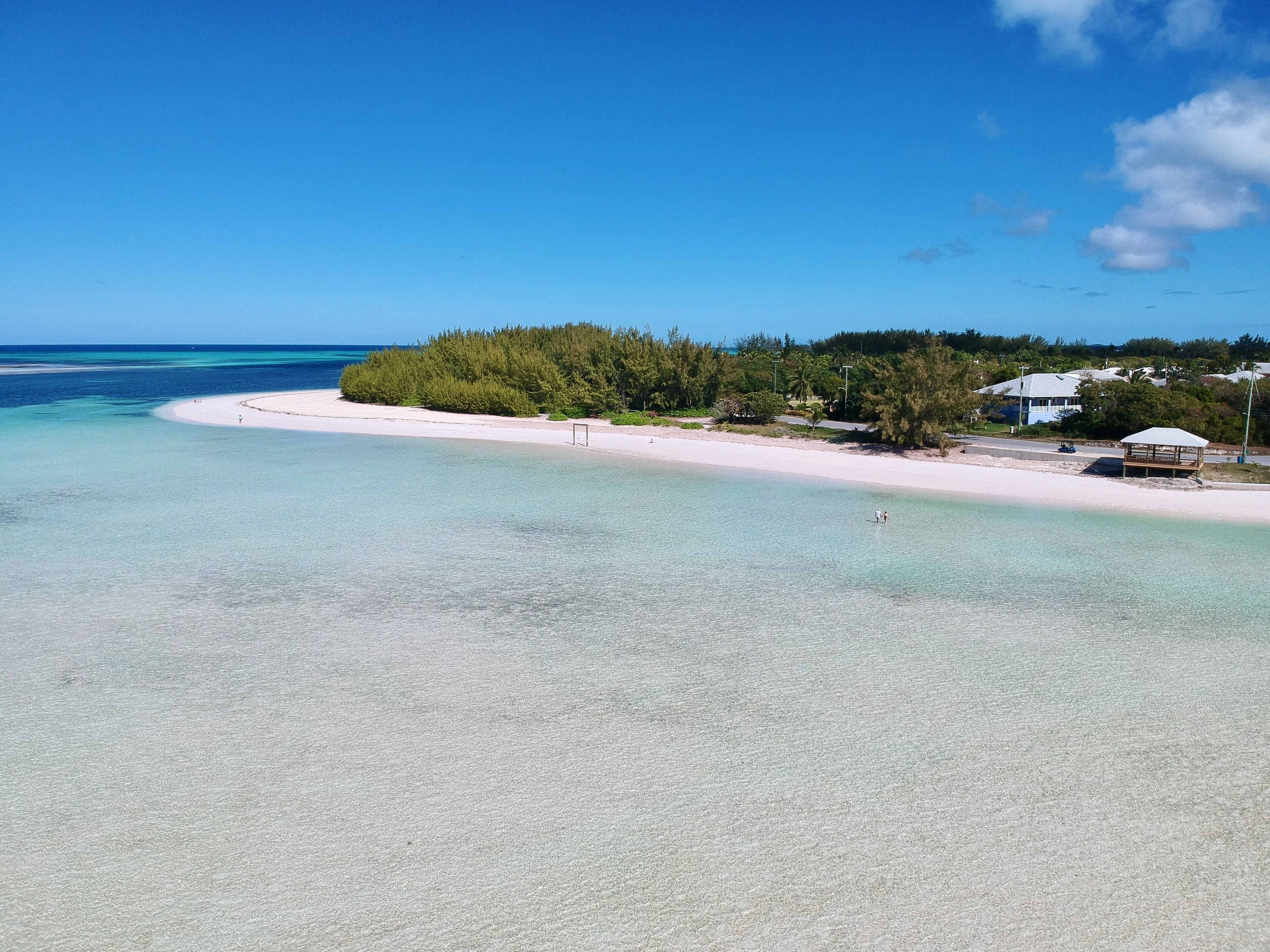 A beach with clear turquoise water, a sandy shore, and a small wooden structure.
