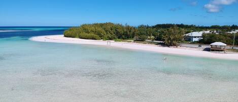 A beach with clear turquoise water, a sandy shore, and a small wooden structure.