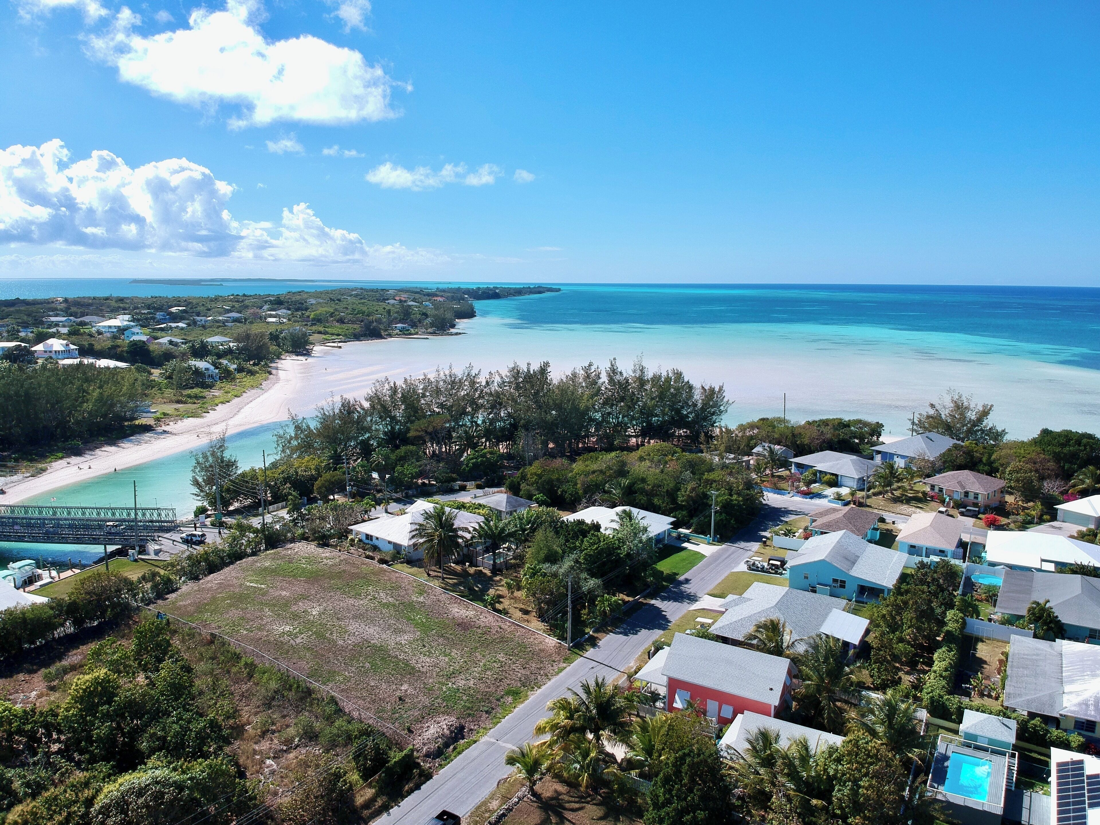 A coastal residential area with houses, a beach, and a pier.