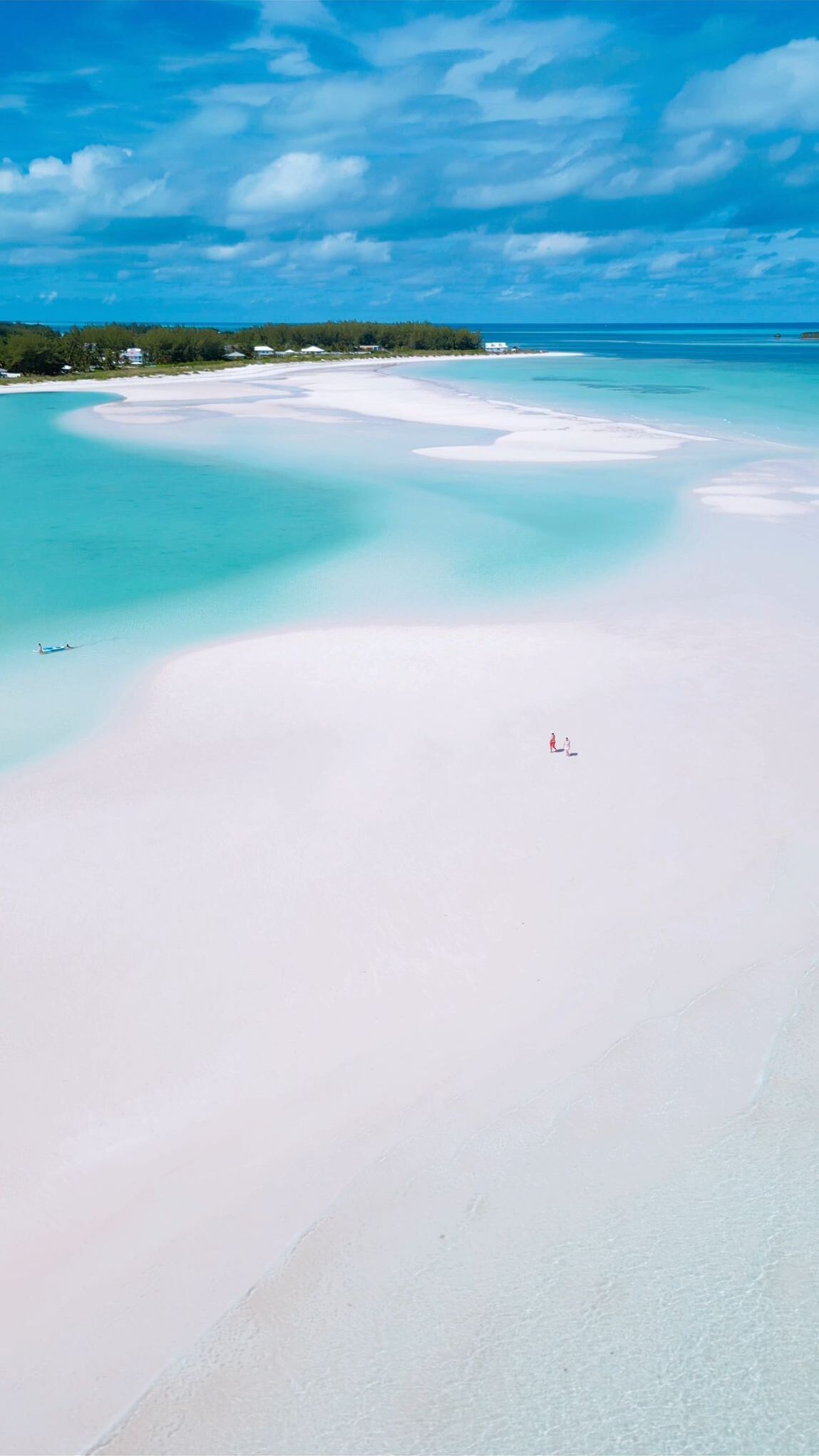 Vue aérienne d’une plage aux eaux turquoise et limpides et au sable blanc.