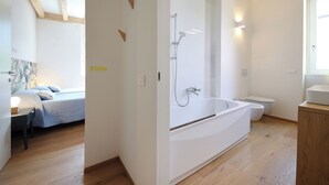 A modern bathroom with a large bathtub, a shower, and a toilet. - Nine Rooms Suites (Trento)