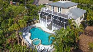 A large house with a swimming pool, surrounded by lush greenery and a view of the sea. - Siesta Key Complete House - Pool - Jacuzzi - 3 Bedroom - 2 Bath - Screened Patio (Sarasota)
