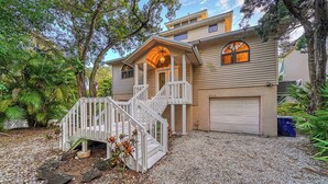 A two-story house with a covered porch, a front staircase, and a garage. - Siesta Key Complete House - Pool - Jacuzzi - 3 Bedroom - 2 Bath - Screened Patio (Sarasota)