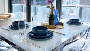 Un espace repas moderne avec une table en verre, des assiettes bleues et une bouteille de champagne.