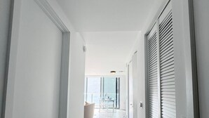 A narrow hallway with white walls and a wooden floor. - Luxury Brickell Studio ✨ Ocean Views + Rooftop Pool + Gym (Miami)