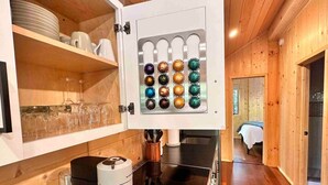 Une cuisine équipée d’un appareil à café intégré, d’une cuisinière et d’une étagère pour ranger la vaisselle.