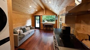 L’intérieur chaleureux d’un chalet avec un plafond en bois, un canapé, une table à manger et un coin cuisine.