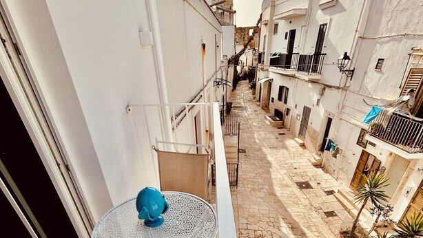 A narrow alleyway with a small balcony featuring a round table and a chair. - La Piazzetta, Luxury Charming Balcony Room, a few steps from the beach  (Polignano a Mare)