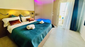 A hotel room with a bed, pillows, a towel, a wall-mounted light, and a view of the outside. - La Piazzetta, Luxury Charming Balcony Room, a few steps from the beach  (Polignano a Mare)