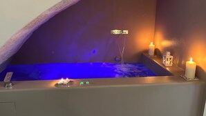 A small, intimate hot tub area with a curved ceiling, a water feature, and candles for ambiance.