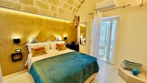A bedroom with a large bed, a stone wall, an air conditioning unit, and a view through a door.