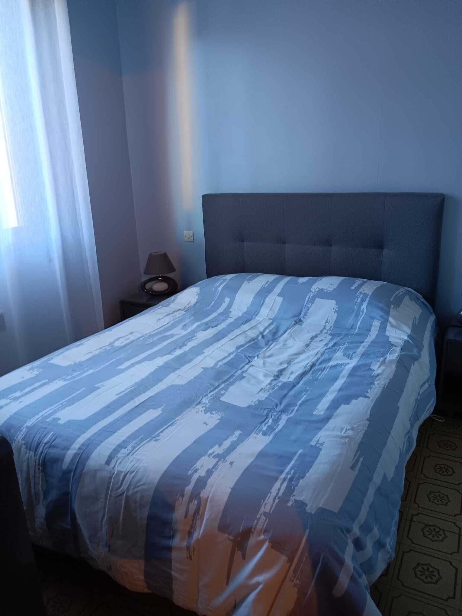 Une chambre d’hôtel avec un lit, une table de chevet, une lampe et une fenêtre avec des rideaux.