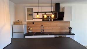 Una cocina moderna con una isla central, horno integrado y un protector de pared de madera.