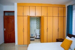 Une chambre à coucher avec un lit, une armoire et une salle de bain visible à travers une porte ouverte.