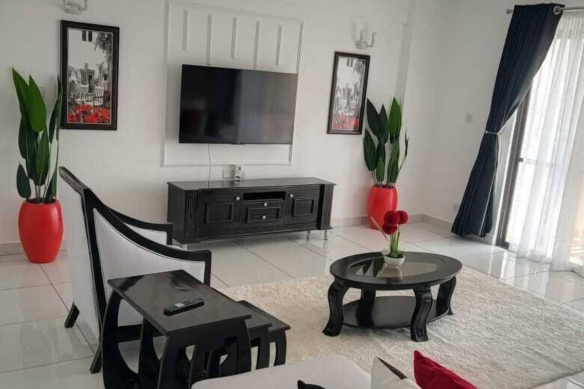 A modern living room with a sofa, coffee table, TV, and potted plants.
