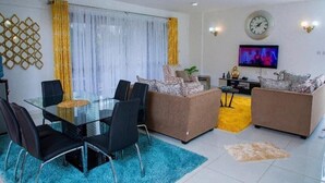 Ein modernes Wohnzimmer mit einem Glastisch, zwei Sofas, einem Fernseher und einer Wanddekoration.