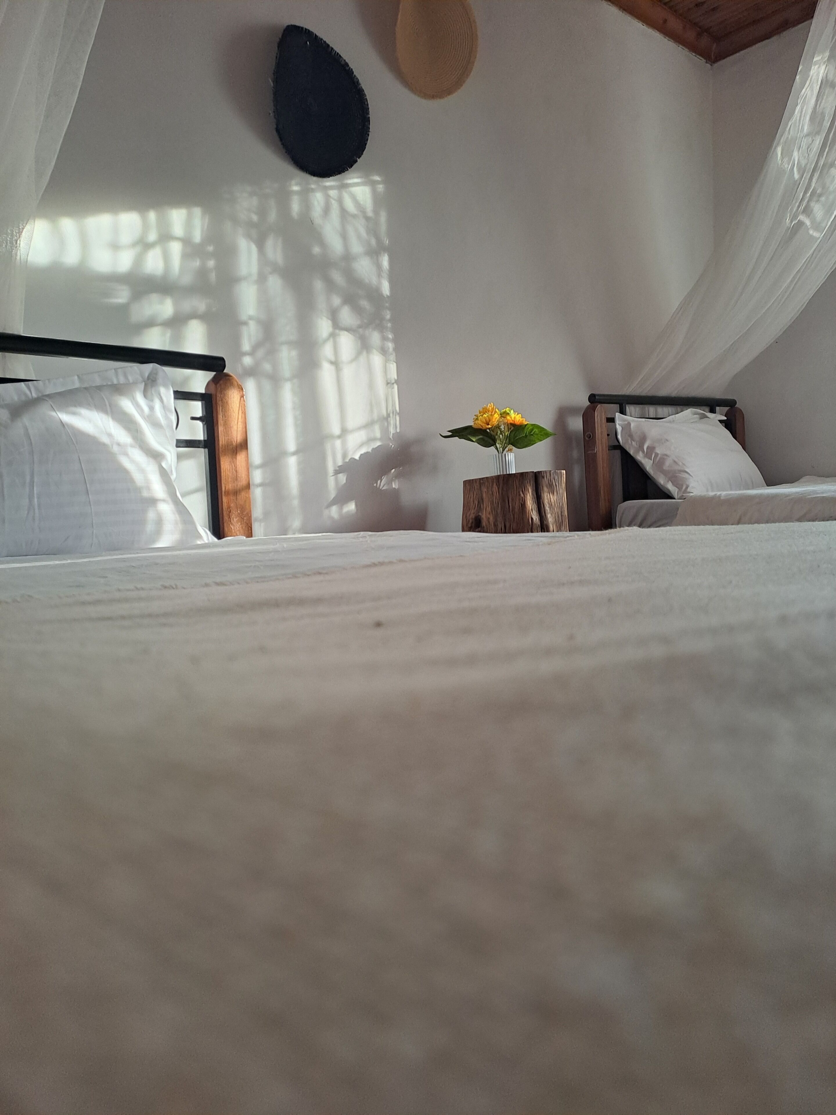 A bed with white linens, a wooden headboard, and a bedside table with a vase of yellow flowers.