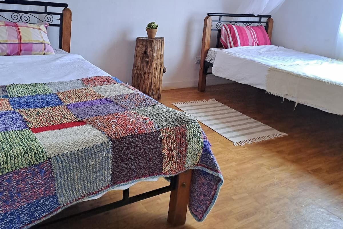 A bedroom with two beds, a wooden floor, and a ceiling fan.