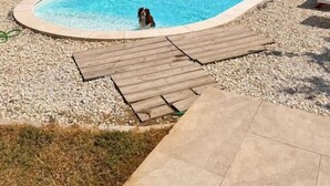 A pool with a stone wall and a view of the sea.