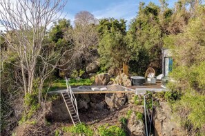 A natural setting with a wooden bridge, a ladder, and a seating area with chairs and a table. - Dolce Lava - Natural Luxury Experience (Valverde)