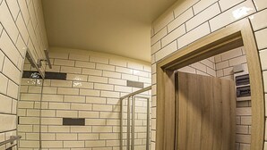 Une salle de bain avec un mur recouvert de carreaux blancs, une porte en bois, un lavabo et des toilettes.