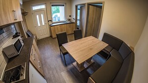 Une cuisine de taille réduite avec un coin repas, comprenant une table en bois et des sièges rembourrés.