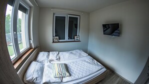 Une chambre à coucher avec un lit, une fenêtre, un téléviseur et un cadre photo accroché au mur.