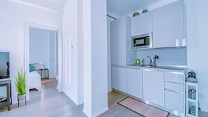 Une cuisine moderne avec des meubles blancs, un four à micro-ondes et un petit îlot central doté d’un évier.