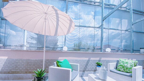 Un espace extérieur aménagé avec des meubles en osier et un grand parasol, baigné de lumi ère naturelle.