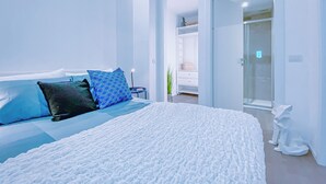 Une chambre à coucher moderne avec un grand lit, un dressing et une douche en verre.