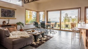 Amplia sala de estar con un ventanal, un sofá, una mesa de centro y un comedor con sillas y una mesa.