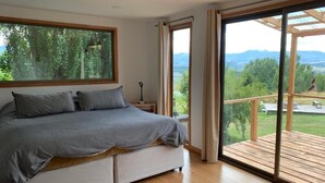 Un dormitorio con una cama grande, vista a una terraza y suelo de madera.