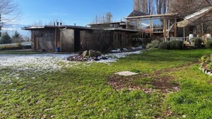 Una casa moderna con una amplia extensión de vidrio, fachada de piedra y un jardín cuidado.