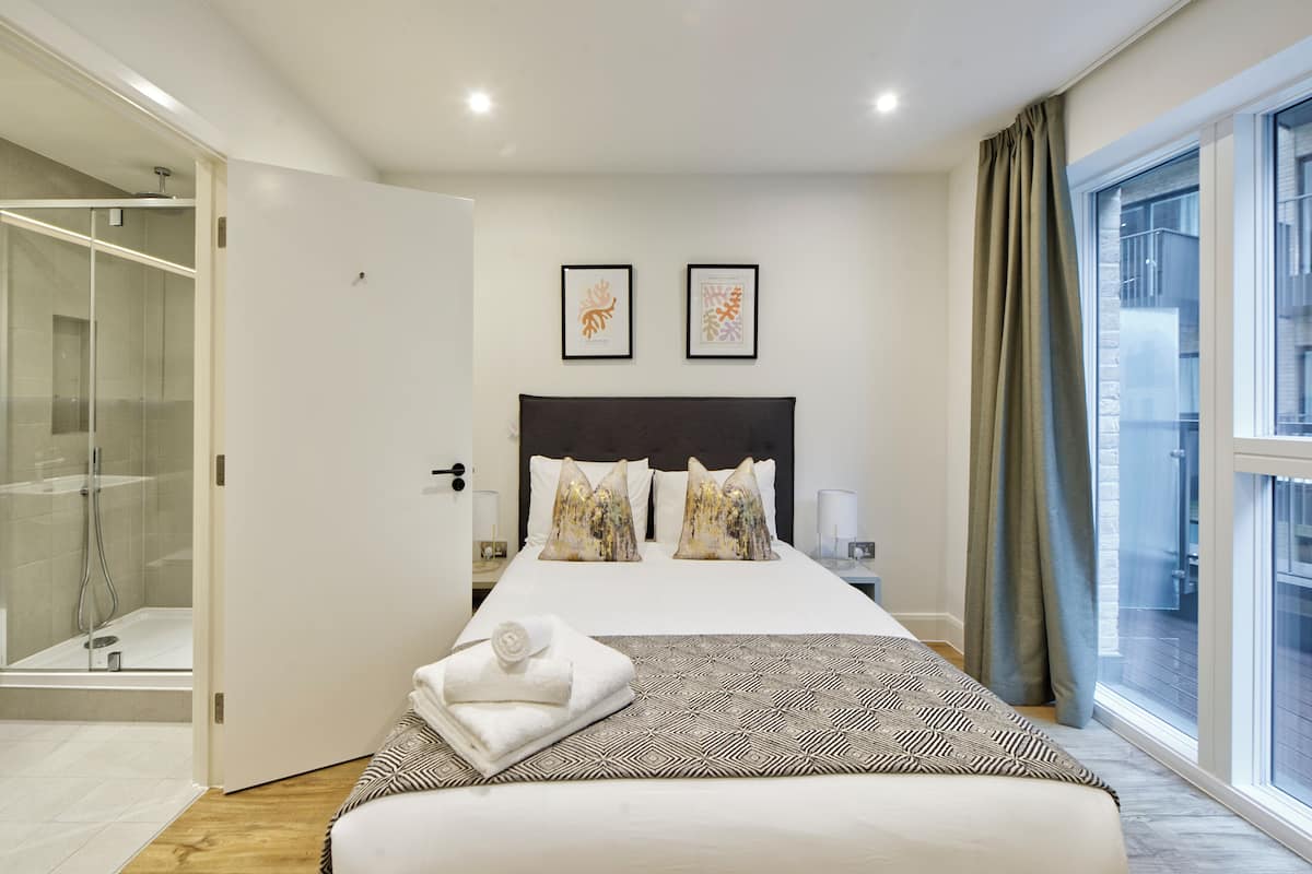 Une chambre d’hôtel avec un grand lit, une douche en verre et une vue sur la ville par une grande fenêtre.