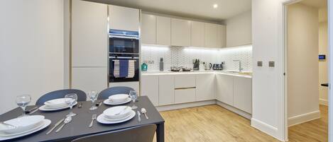A modern kitchen with white cabinets, a built-in oven, and a herringbone backsplash.