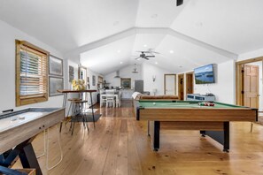A spacious room with a pool table, a dining area, and a television.