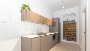 A modern kitchen with a built-in oven, a stainless steel refrigerator, and a wooden accent wall. - GuestReady - Cozy stay near Malvarrosa Beach (Valencia)