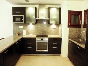 Een koelkast, een microgolfoven, een oven, kookgerei, borden en bestek