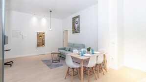 Un salon moderne comprenant un coin repas, un canapé bleu clair, un panneau mural pour plantes et un tableau.