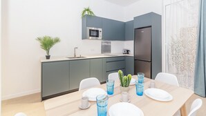 Une cuisine moderne avec des meubles gris, un four à micro-ondes encastré et un réfrigérateur en acier inoxydable.