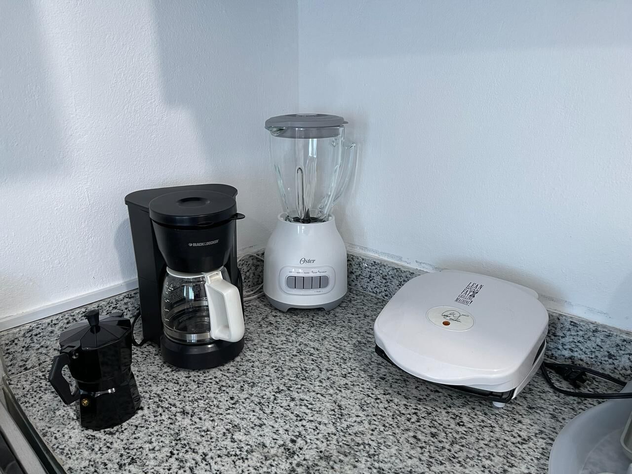 A kitchen counter with a coffee maker, a blender, and a scale.