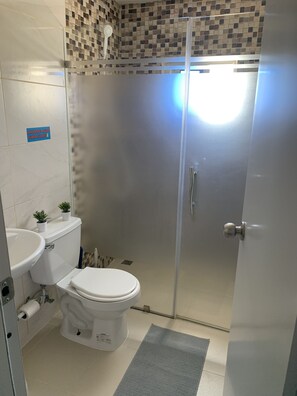 A bathroom with a toilet, sink, and shower area. - Plata View Apartahotel (Monte Plata)