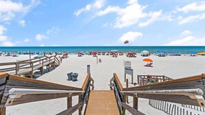 A wooden staircase leading to a beach with umbrellas and sun loungers. - Ocean Breeze East 201 (Pensacola)